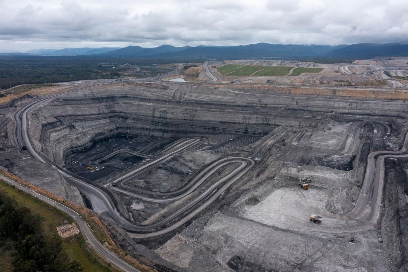 Aerial view of a regional open-cut mining operation with ranges beyond