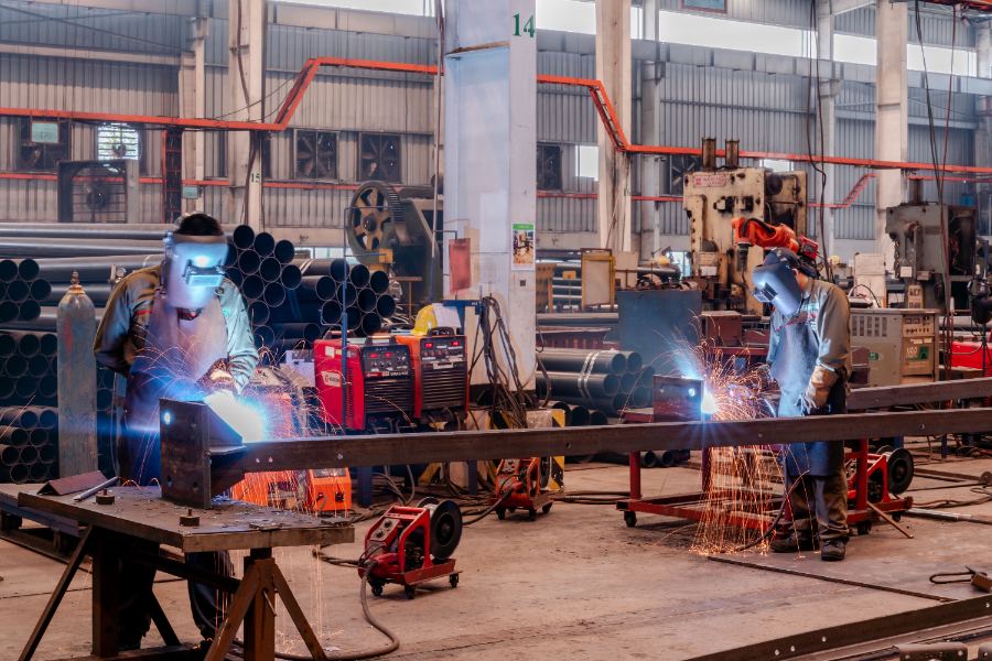 Boilermakers welding structural steel in a fabrication workshop